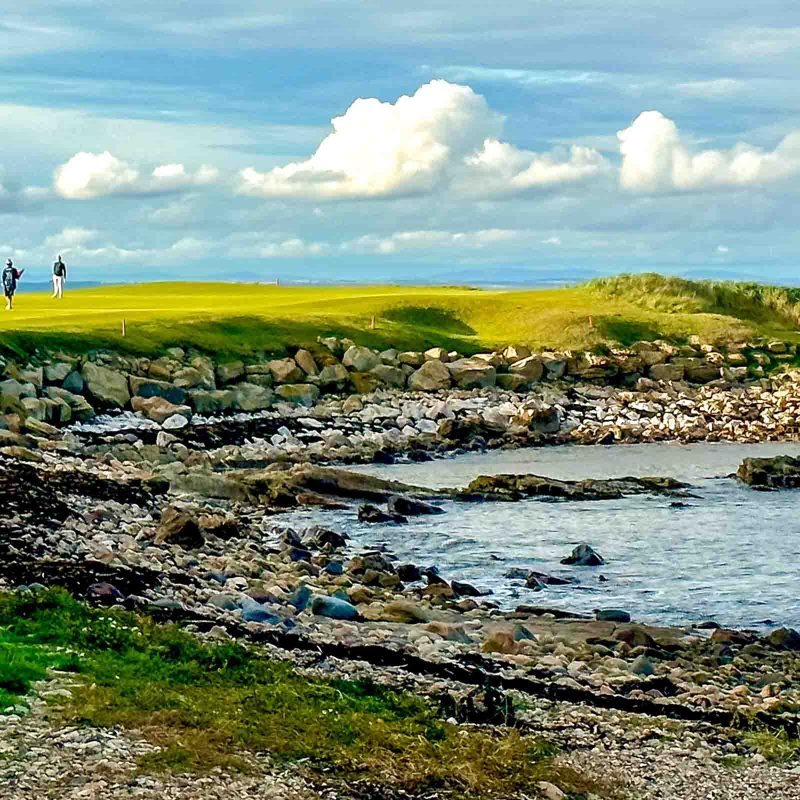 Outside at St Andrews with golfers playing nearby.